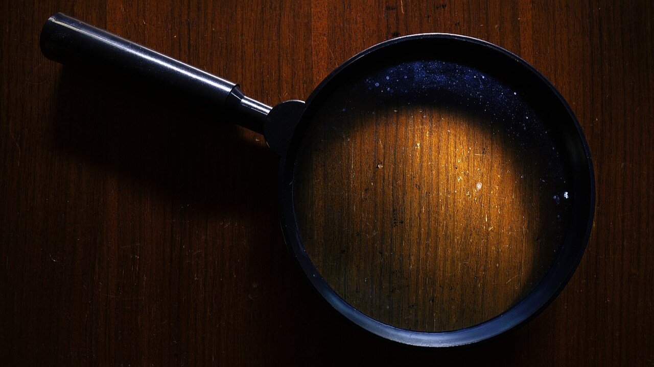 An old, dirty magnifier on a dark wooden background.